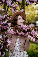 Fototapeta premium Young girl with hat in a sakura garden