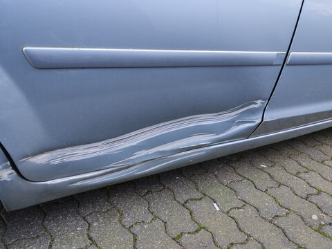 Blue car door with a very large scratch after hitting a wall