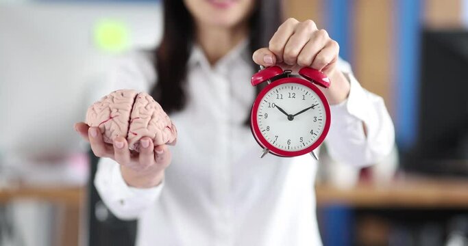 Businesswoman holding artificial mock human brain and red alarm clock in her hands closeup 4k movie slow motion. Business strategy concept