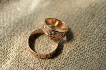 Obraz na płótnie Canvas Latvian ancient symbols. Gold wedding rings with ancient symbols. Rings on linen fabric. 
