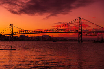 Silhouette of cable bridge with sunset sky and reflection on water in Florianopolis, Brazil
