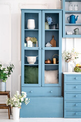 Blue wooden cupboard with glass doors, vases, teapots and jars