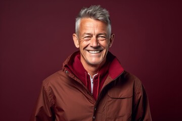 Fototapeta premium Lifestyle portrait photography of a grinning mature man wearing a lightweight windbreaker against a rich maroon background. With generative AI technology