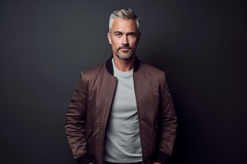 Fototapeta premium Lifestyle portrait photography of a tender mature man wearing a sleek bomber jacket against a dark grey background. With generative AI technology
