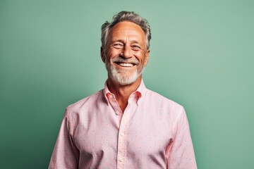 Lifestyle portrait photography of a joyful mature man wearing a classy button-up shirt against a pastel green background. With generative AI technology