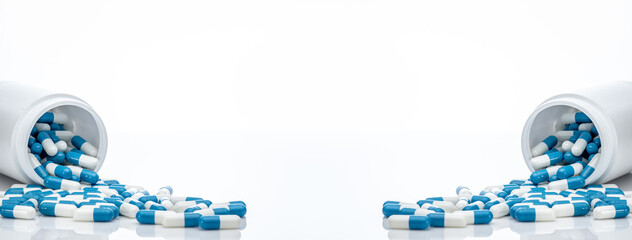 Blue-white antibiotic capsule pills spread out of plastic drug bottles. Antibiotic drug resistance....