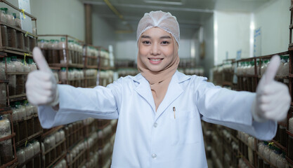 Portrait of young asian muslim female scientist doing research at a mushroom factory, examining mushroom leavening agent in a sterile and temperature-controlled room.