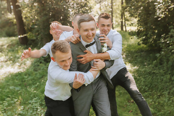 Fototapeta premium The groom celebrates his wedding with friends outdoors after the ceremony