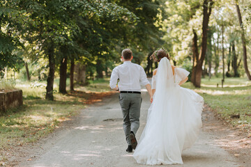 A wedding couple, a happy bride and groom are running in the park to the place of the wedding ceremony. Wedding concept