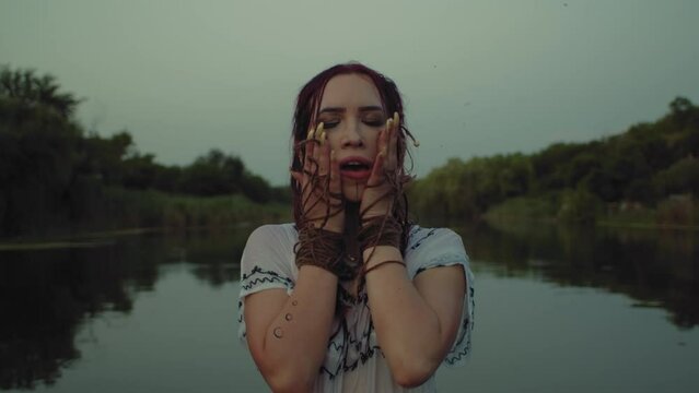 In the realm of spirits and ancient traditions, a female shaman engages in a spellbinding ritual by the river, her costume and ceremonial practices embracing the essence of magic and spirituality.