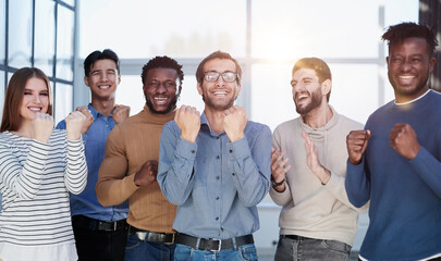 Fototapeta premium Group of happy managers rejoice at a successful deal by clenching their hands into fists and raising them up