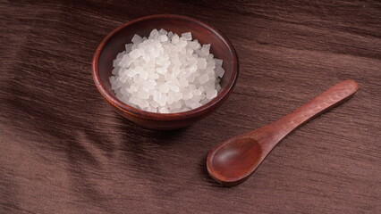 Wooden Spoon with white sugar on the dark background.