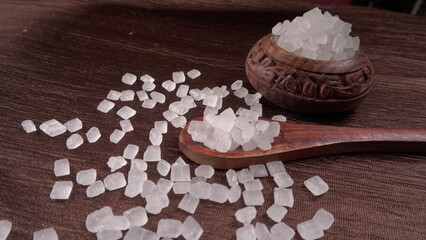 Wooden Spoon with white sugar on the dark background.