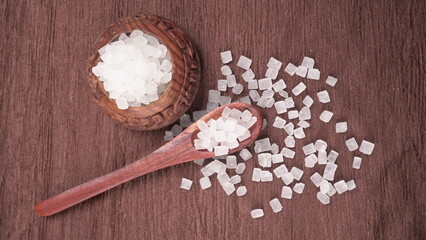 Wooden Spoon with white sugar on the dark background.