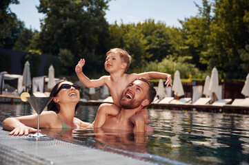 Having fun. Happy family of father, mother and son are in the pool