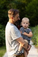 Fototapeta premium Young father with his little son walking in the park on a sunny day