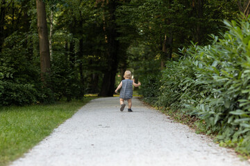 Fototapeta na wymiar Little boy running on the road in the park. Summer time.
