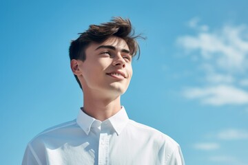 Close-up portrait photography of a satisfied boy in his 20s wearing an elegant long-sleeve shirt against a sky-blue background. With generative AI technology