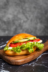 Sandwich with cheese, tomato, cucumber and lettuce. Delicious sandwich on wood serving board