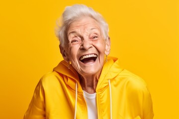 Headshot portrait photography of a happy old woman wearing a comfortable tracksuit against a yellow background. With generative AI technology