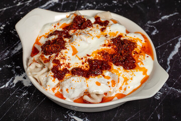 Ravioli with sauce and yogurt. Ravioli on a dark background. Turkish cuisine delicacies. Close up