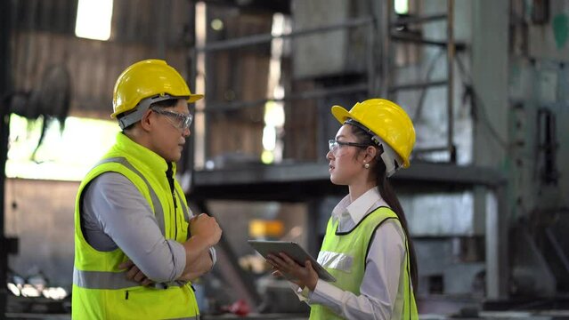 asian industrial Engineer manager man discussion with mechanic worker woman using tablet checking industry manufacturing large factory . two Contractor talking and inspection Construction site