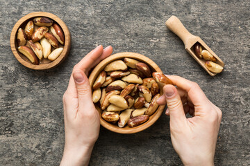 Woman hands holding a wooden bowl with brazil or bertholletia nuts. Healthy food and snack. Vegetarian snacks of different nuts