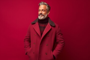 Fototapeta premium Lifestyle portrait photography of a satisfied mature man wearing a cozy winter coat against a ruby red background. With generative AI technology