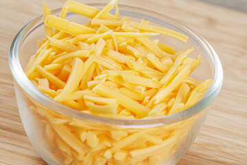 Close up of delicious Grated Cheddar Cheese on wooden background