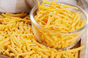 Close up of delicious Grated Cheddar Cheese on wooden background