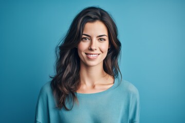 Close-up portrait photography of a satisfied girl in her 20s wearing a simple tunic against a cerulean blue background. With generative AI technology