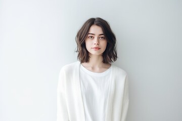 Obraz premium Conceptual portrait photography of a satisfied girl in her 20s wearing a chic cardigan against a minimalist or empty room background. With generative AI technology
