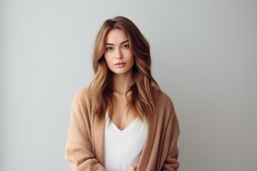 Obraz premium Conceptual portrait photography of a satisfied girl in her 20s wearing a chic cardigan against a minimalist or empty room background. With generative AI technology
