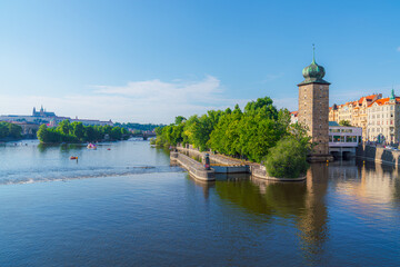 A tranquil scene of the Vltava River in Prague, Czech Republic, with boats gliding past the...