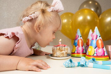 A two-year-old girl blows out a candle on a birthday cake, makes a wish