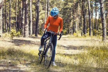 Obraz premium woman cyclist rides in the forest on a mountain bike.