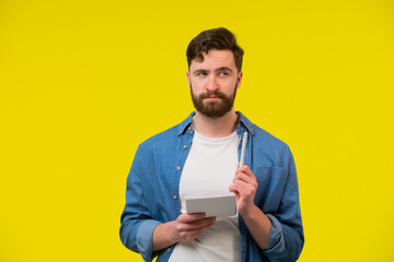 Young man holding a notepad, pen and thinking about ideas