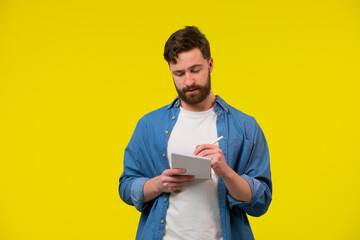 Young man holding a notepad in hand and writing something in it