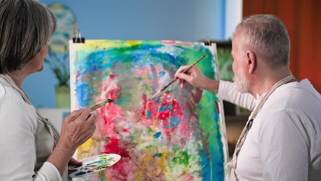creative hobby in retirement, adorable elderly pensioners painting creative picture together with paints and brushes at home