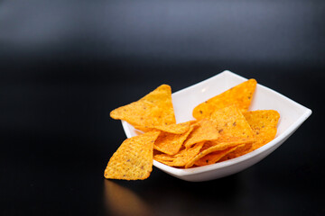 mexican nachos in a bowl on black background with copy space
