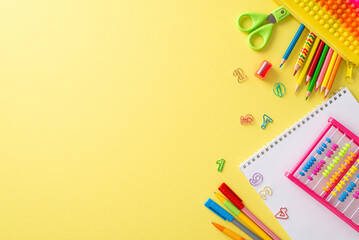 Delve into the world of education with this top-view photograph featuring album, abacus and other stationery on an isolated yellow background. Utilize the copy-space for text or advertising