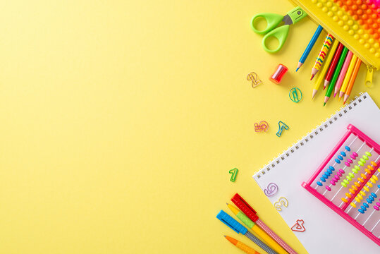 Delve into the world of education with this top-view photograph featuring album, abacus and other stationery on an isolated yellow background. Utilize the copy-space for text or advertising