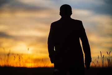 Silhouette of a businessman at sunrise in nature. The concept of business, negotiations, development, success, startups, new opportunities