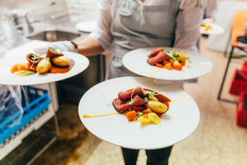 Waitress serving plates with roast beef and potatoes in restaurant.