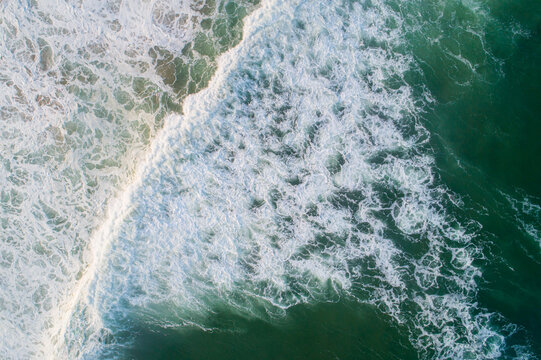 aerial view of some ocean waves breaking on a green water sea