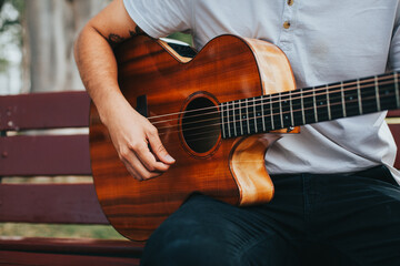 Fototapeta premium detail photograph of young man playing acoustic guitar outdoors. Concept of people, musicians and hobbies.