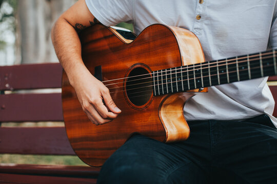 detail photograph of young man playing acoustic guitar outdoors. Concept of people, musicians and hobbies.