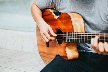 detail photograph of young man playing acoustic guitar outdoors. Concept of people, musicians and...