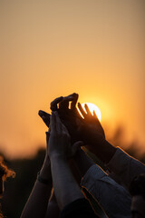 Multiracial group of diverse young people giving high five against a setting sun, feels excited...