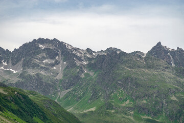 Obraz premium Steinige, steile Berge zwischen Tirol und Vorarlberg, Österreich, mit Schnee im Sommer und grünen Weiden aus dreistufiger Almwirtschaft. Wunderschönes Gebiet zum Klettern und Wandern, Erholung pur 